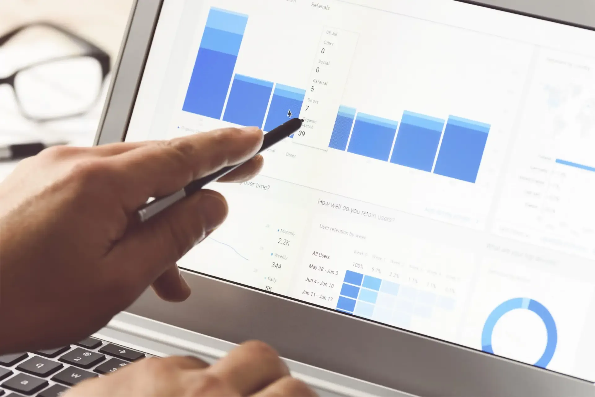 Main pointant un stylo vers des graphiques de statistiques affichés sur un écran