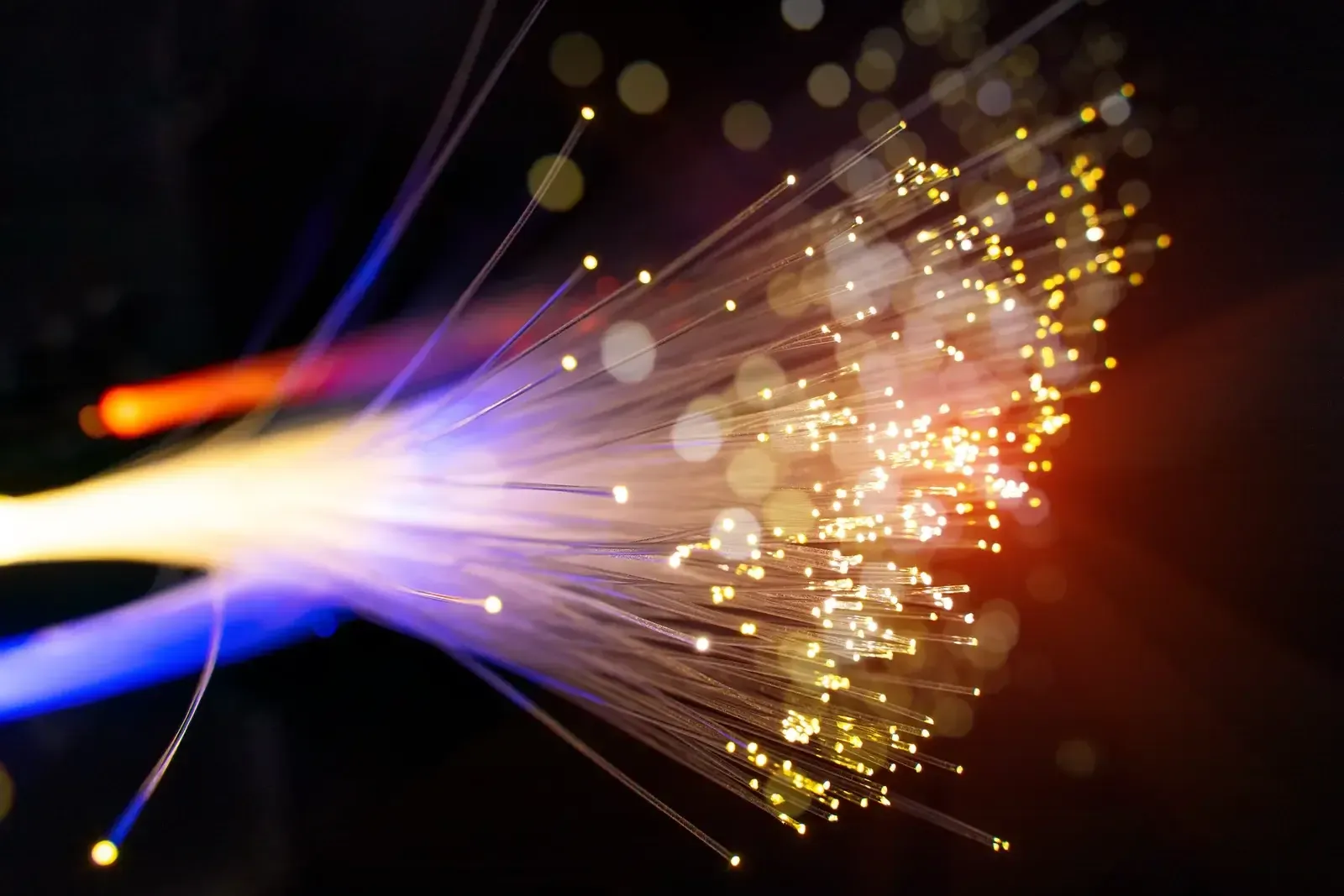 Extrémités lumineuses d’un faisceau de fibres optiques, points ambrés et filets bleus sur fond noir