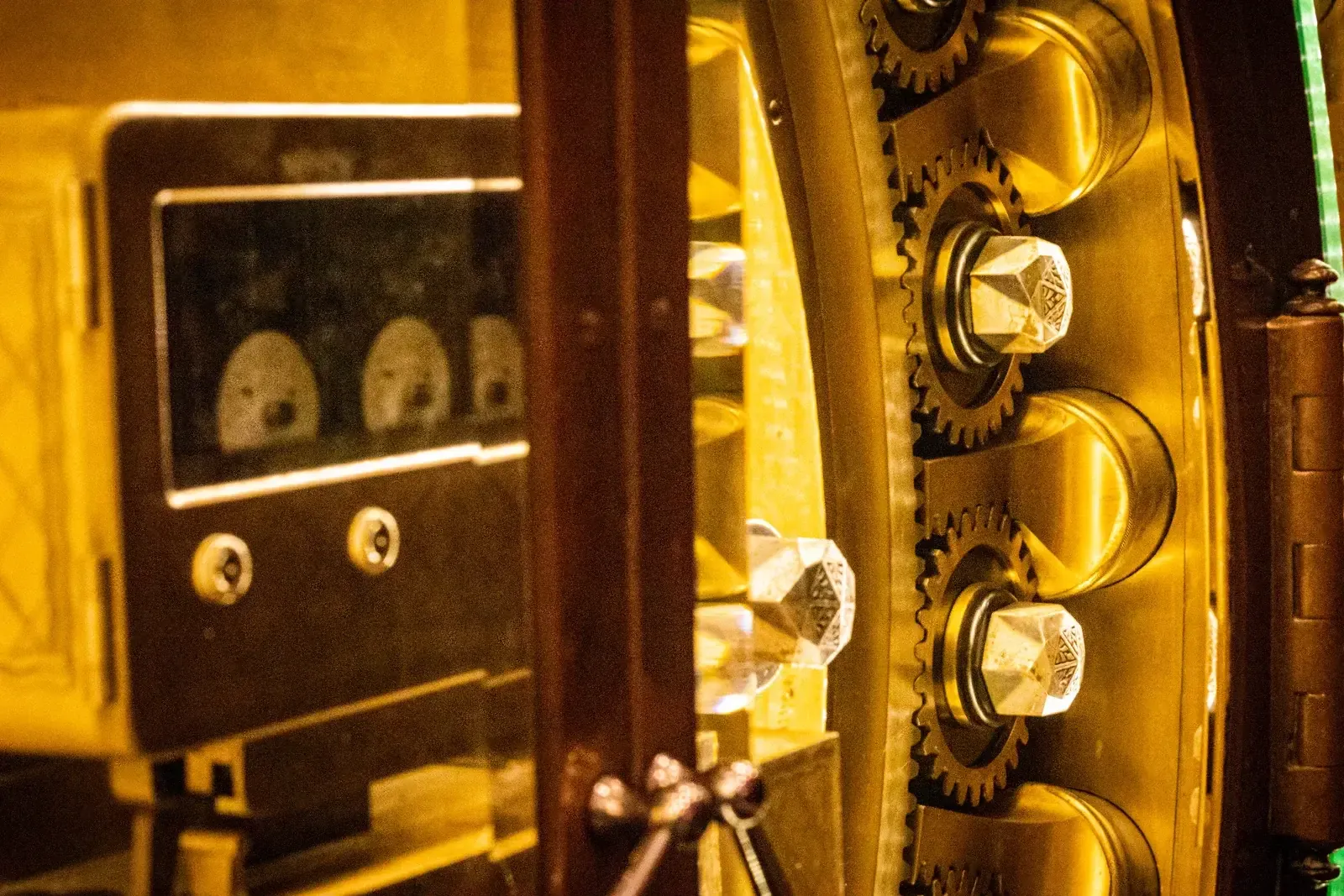 Porte ouverte d’un ancien coffre-fort de banque, gros pênes et engrenages en laiton dans une lumière ambrée