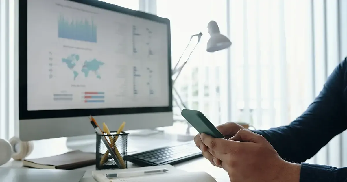 Écran affichant un tableau de bord de mesures, courbes et carte, sur un bureau clair près d'une fenêtre