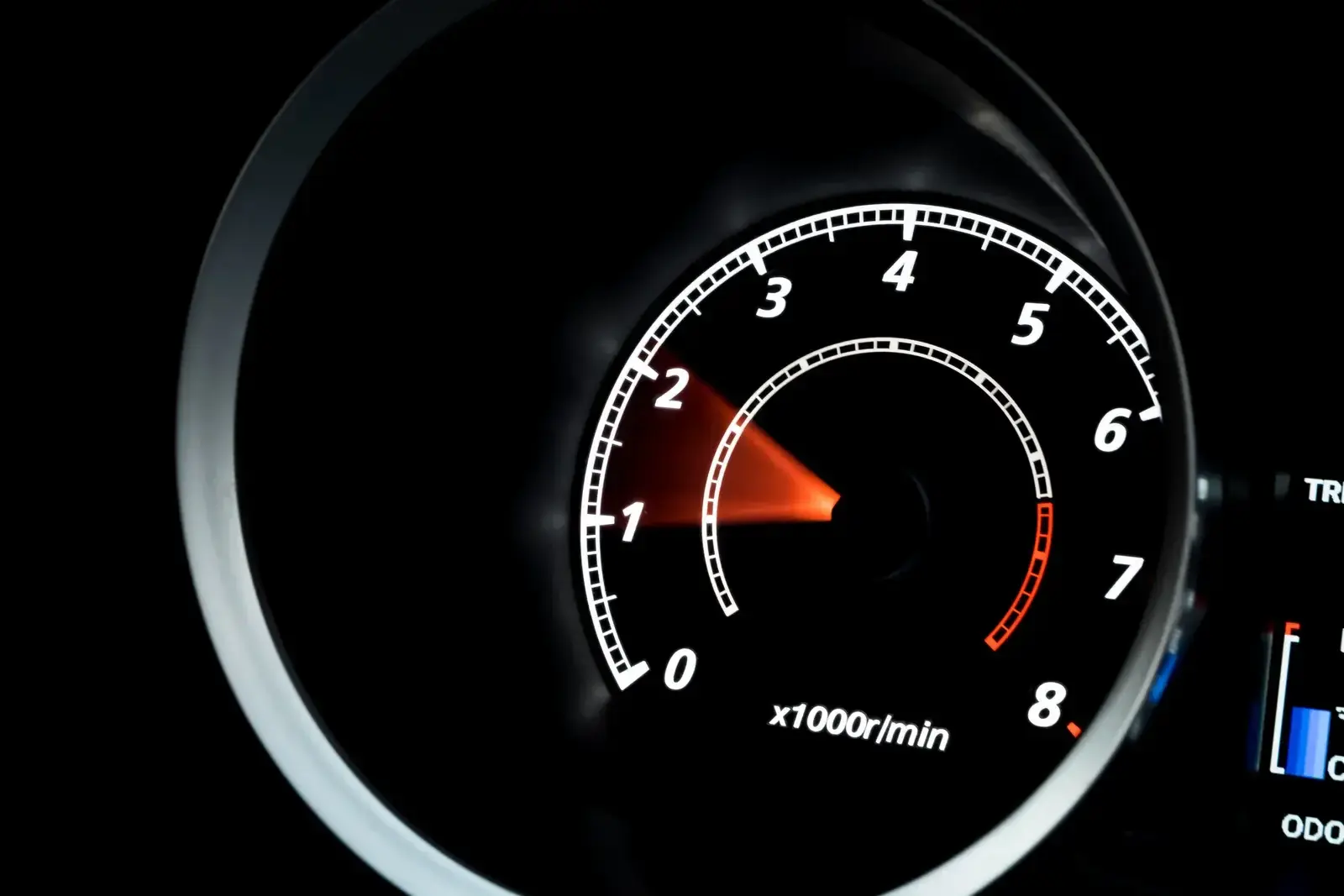 Black rev counter dial marked from 0 to 8, orange needle pointing at the bottom of the scale
