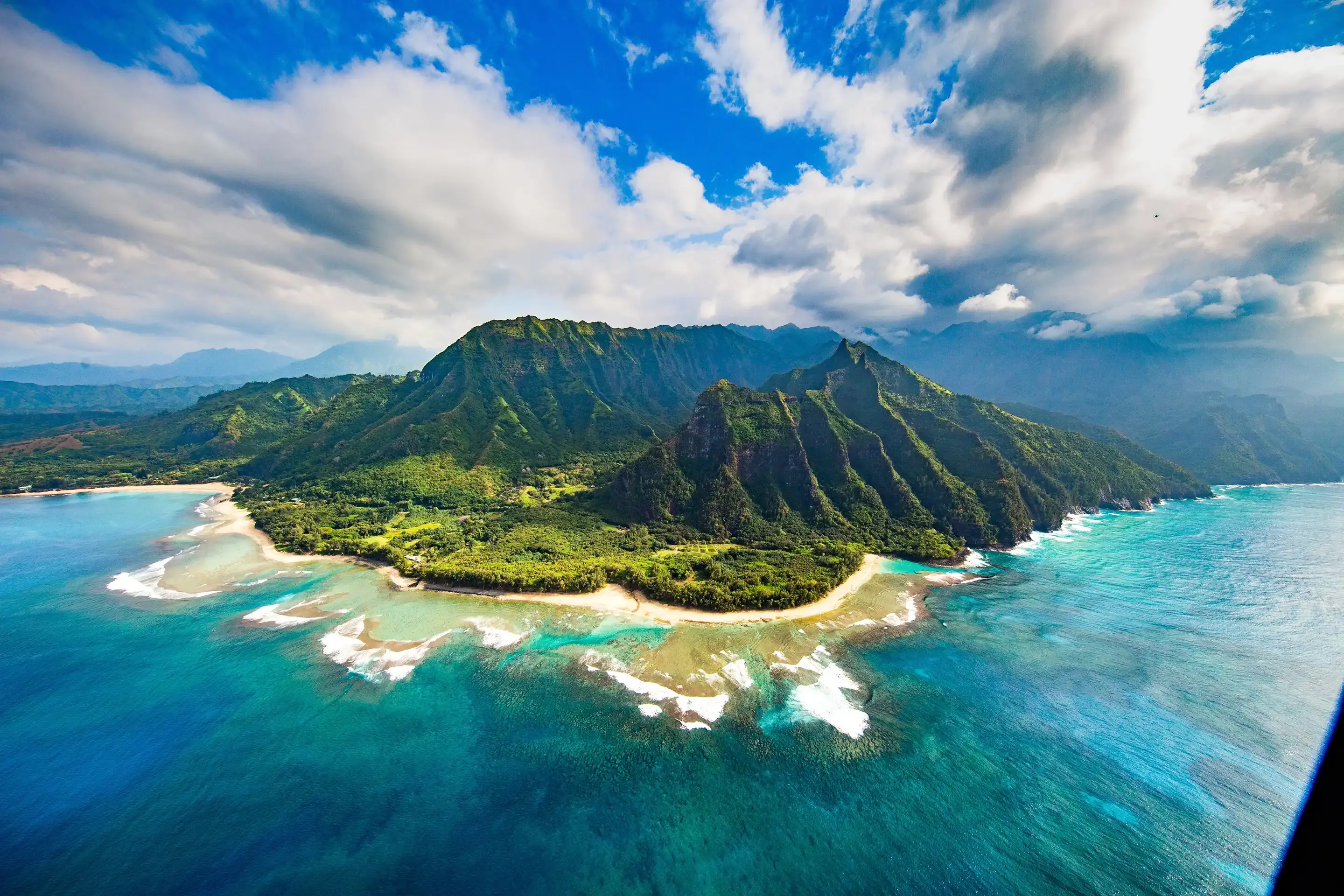 The Na Pali coast seen from the air, green cliffs plunging into a turquoise lagoon