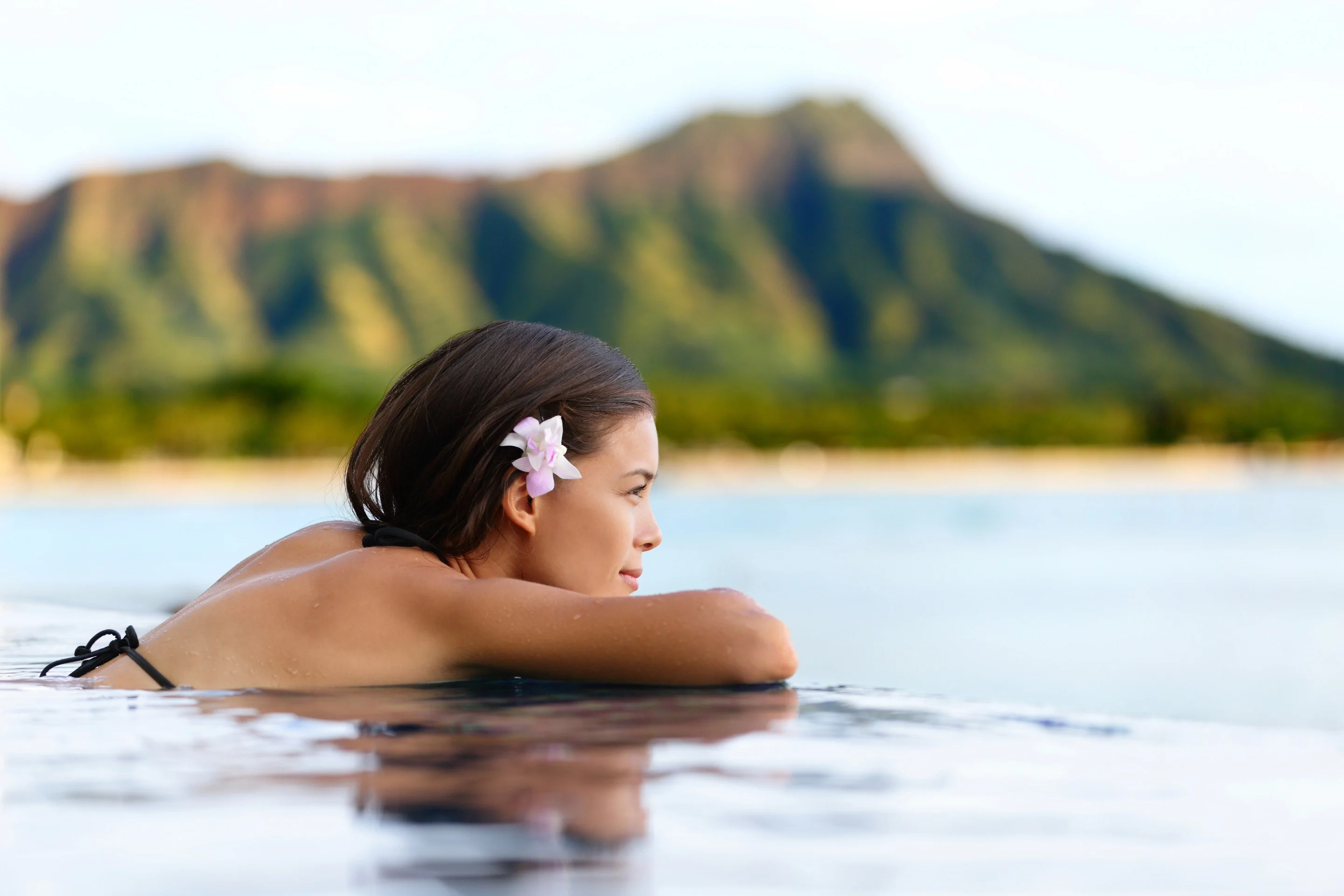 Woman relaxing in the water, facing the Diamond Head crater in Hawaii